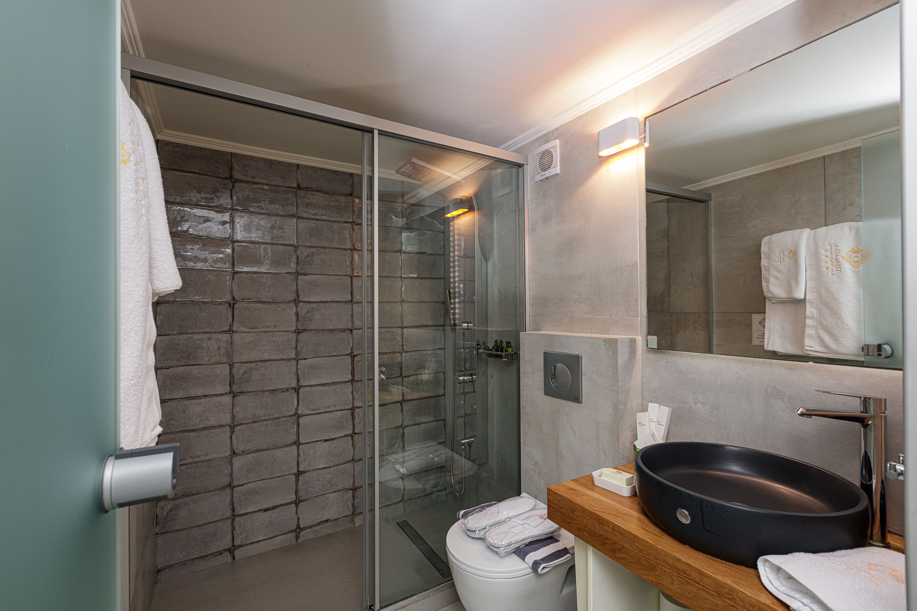 A modern bathroom with a glass-enclosed shower, a wooden vanity, and a large mirror.