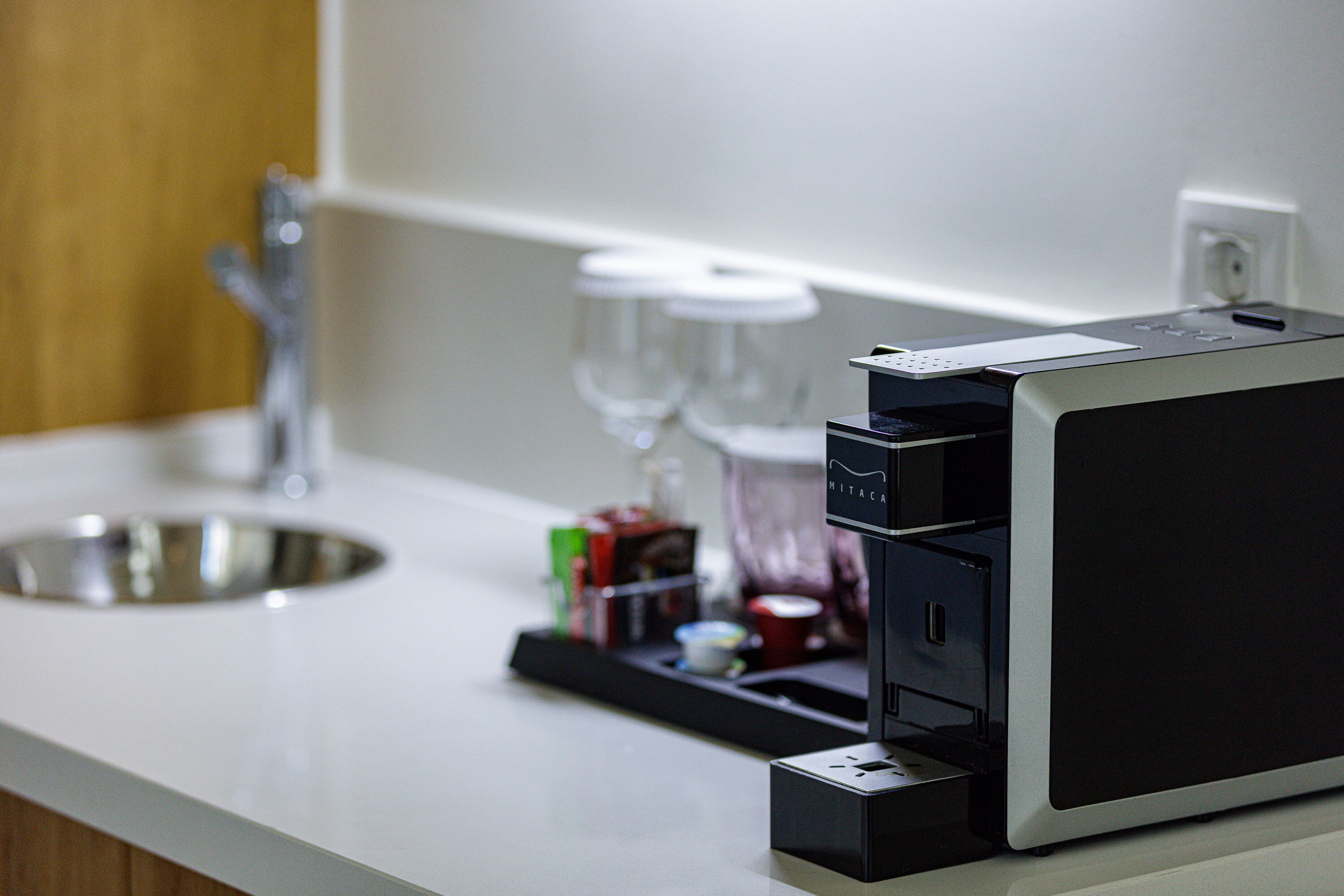 Un comptoir de cuisine avec une machine à café, un évier et un verre à vin.