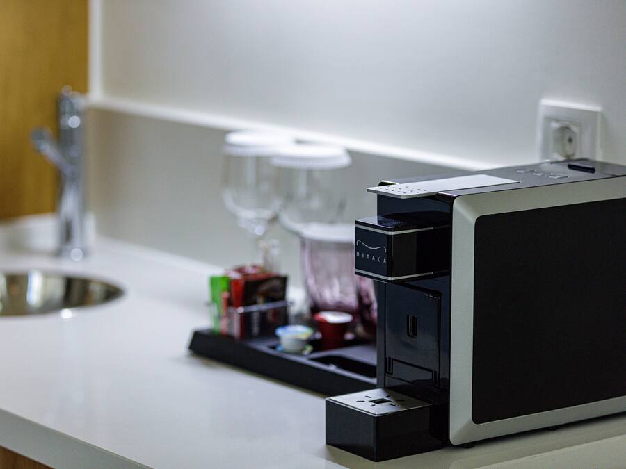 Un comptoir de cuisine avec une machine à café, un évier et un verre à vin.
