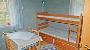 Un dormitorio con literas, una mesa y sillas, una ventana con cortinas y una puerta.