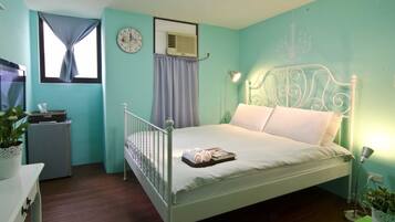 A bedroom with a single bed, a small bedside table, a wall clock, an air conditioning unit, and a window with curtains.