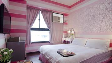 A bedroom with a bed, a vanity with a mirror, and a window with curtains.