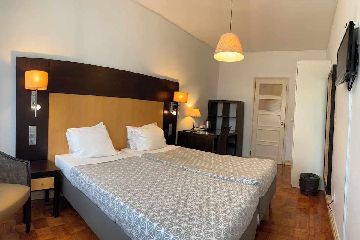 Habitación de hotel con una cama grande, un escritorio, una silla, un armario y un televisor.