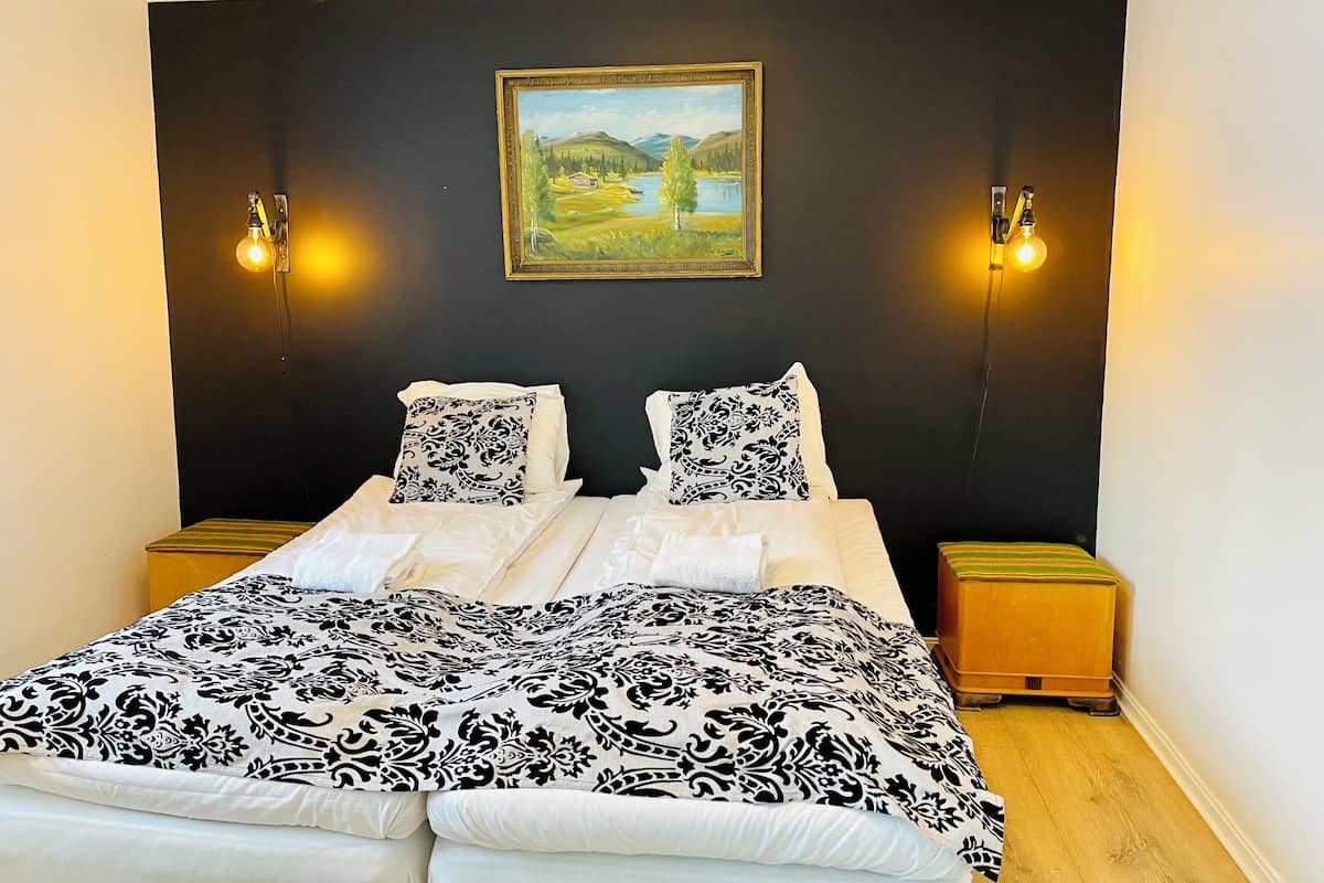 Un dormitorio con una cama, dos mesitas de noche, un cuadro en la pared y luces empotradas.