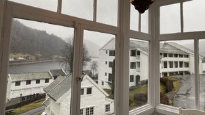 A view through a window with a white building and a river in the background. - Lilandtunet Apartments Voss (Voss)