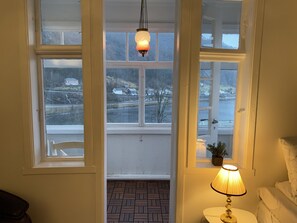 Habitación con vistas a un paisaje nevado a través de amplios ventanales, una lámpara colgante y una mesita de noche con lámpara.