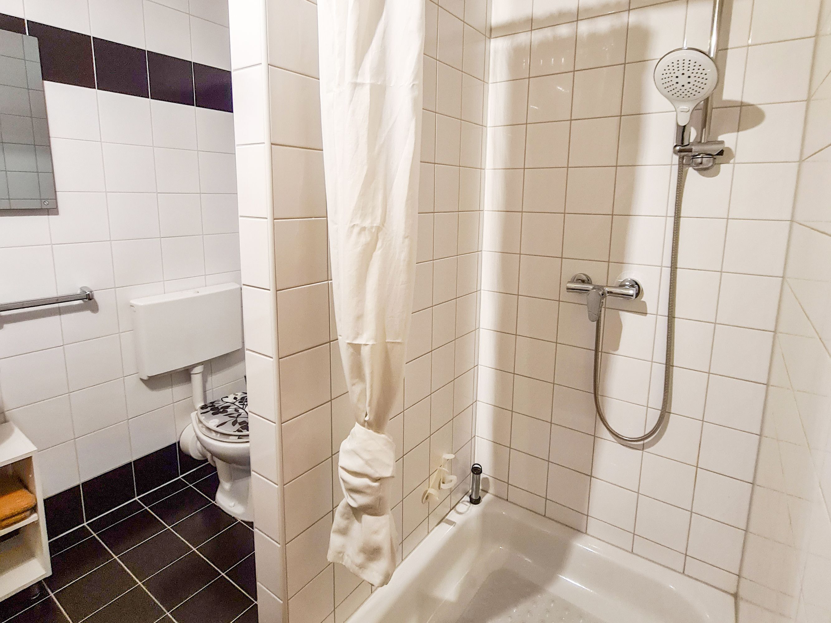 Ein Badezimmer mit Dusche, Toilette und Handtuchhalter.