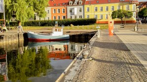 A canal with a boat docked, a bridge, and colorful buildings in the background.
