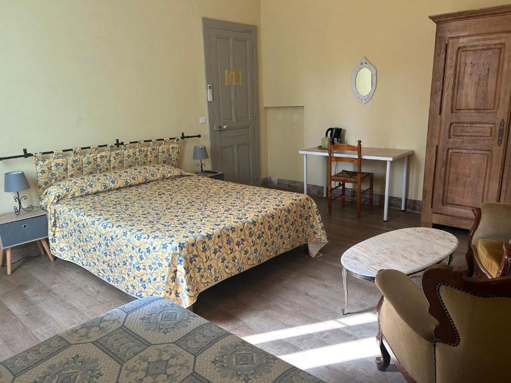 Un dormitorio con cama, escritorio, silla, armario y una mesita.