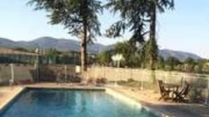 A rectangular swimming pool with a wooden deck and a metal fence. - Le Parc aux Cèdres (Laroque)
