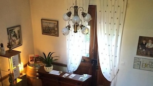 A dining area with a wooden table, chairs, a chandelier, and a patterned rug. - Le Parc aux Cèdres (Laroque)