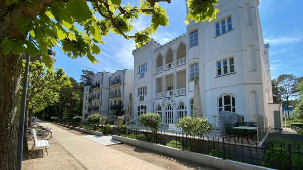 Un immeuble à plusieurs étages doté de balcons, d’une allée pavée et d’une clôture.