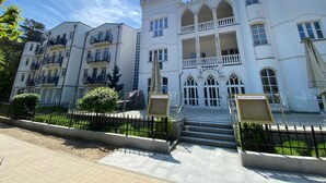 Un hôtel à plusieurs étages, doté d’une façade rappelant un château, de balcons et d’une entrée centrale avec des marches.