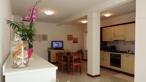 Una cocina compacta con comedor, televisor y una planta decorativa.