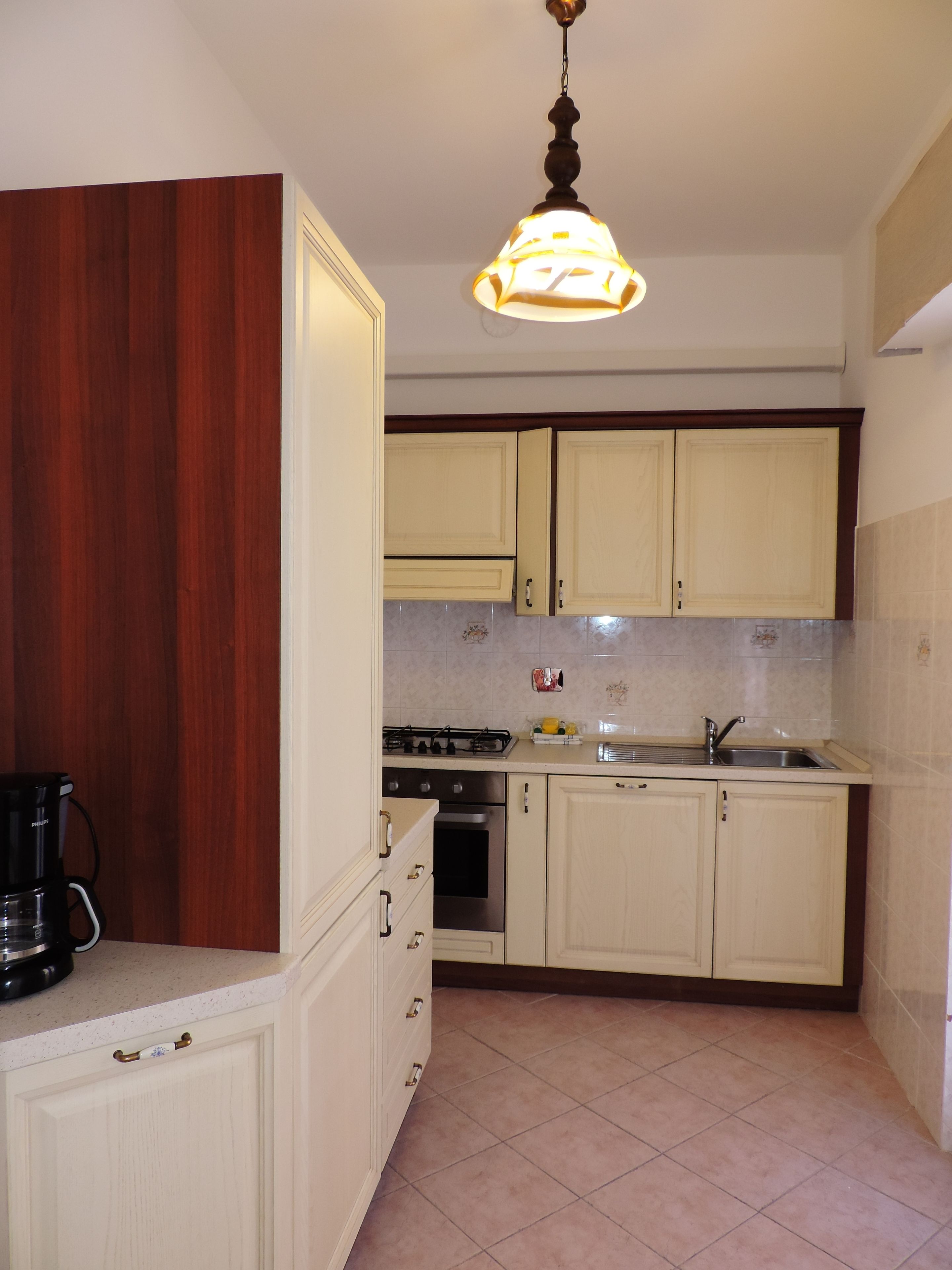 A kitchen with wooden cabinets, a stove, an oven, and a coffee maker.