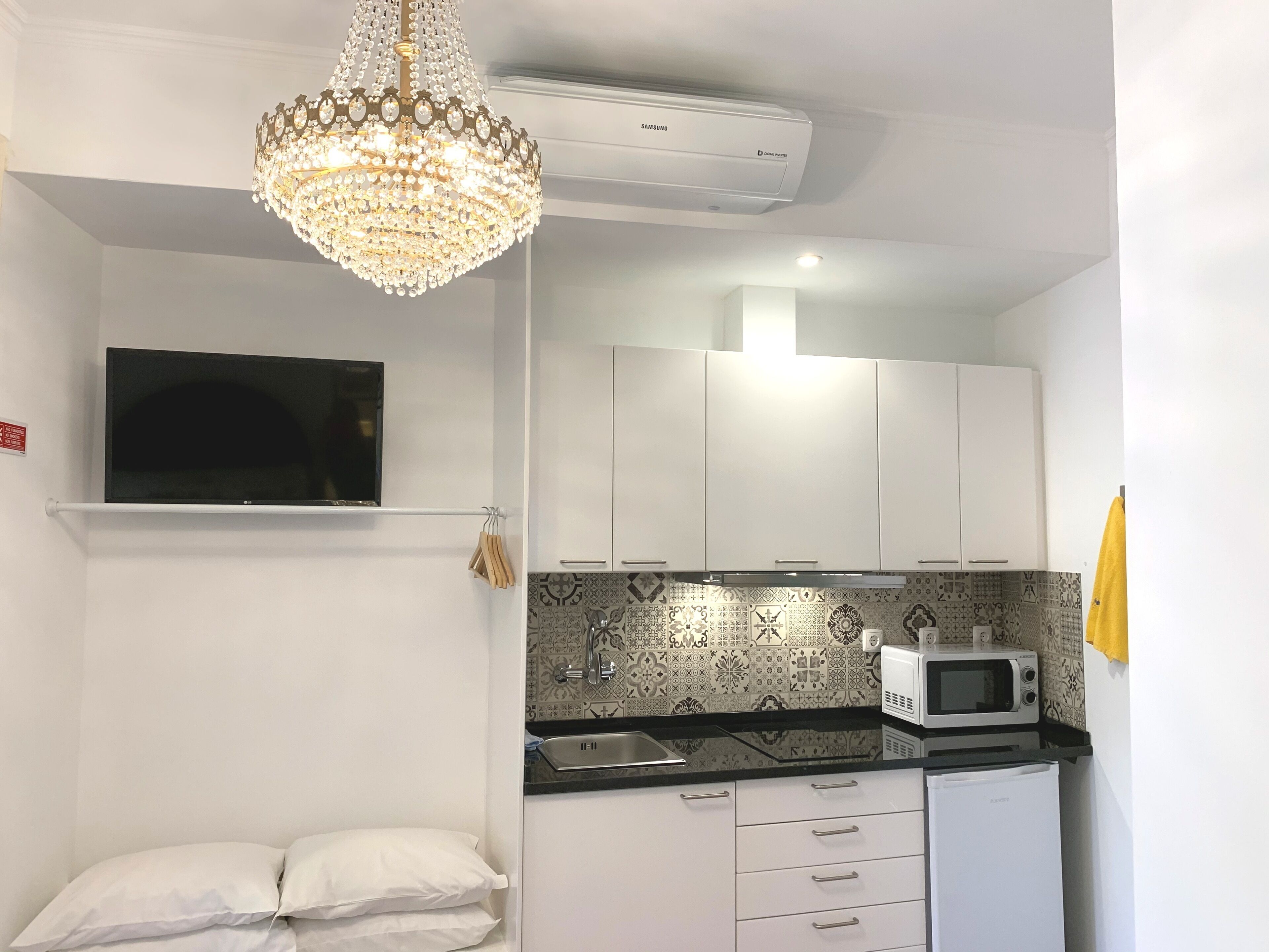 Cocina compacta con armarios blancos, microondas y un salpicadero estampado.