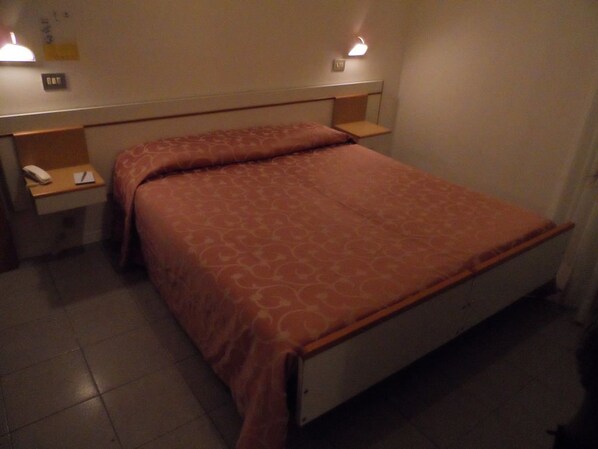 A single bed with a patterned bedspread, a bedside table with a lamp, and a telephone. - Hotel La Dolce Vita (Rimini)