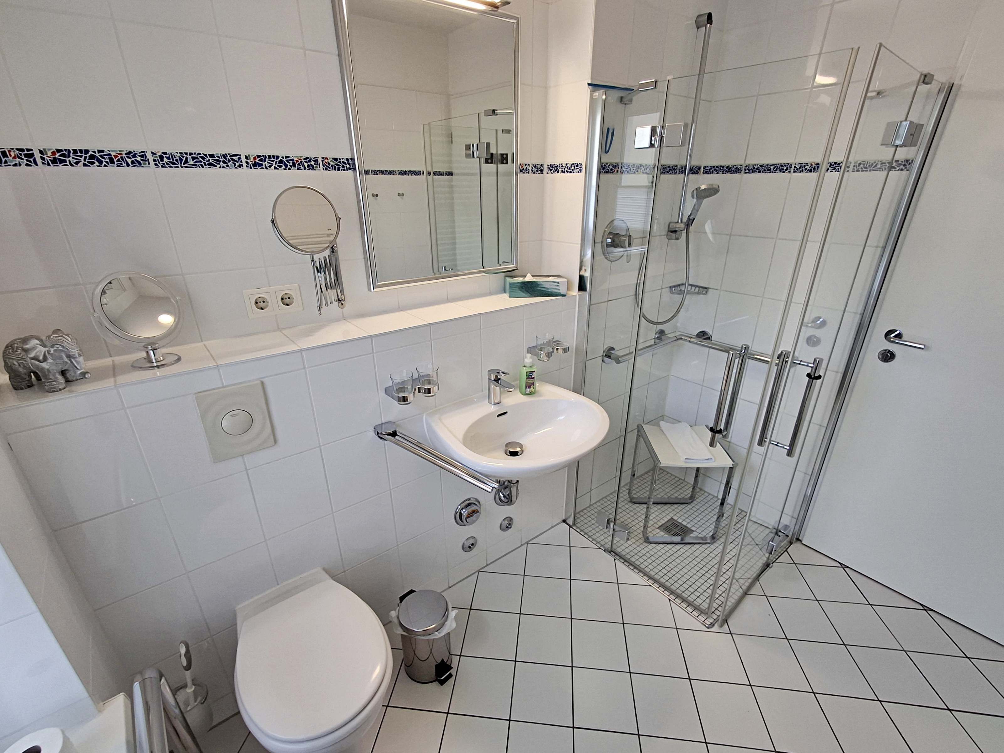 Ett modernt badrum med en dusch som är avskärmad med glasväggar, en vit tvättställ och en toalett.
