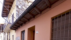 A narrow cobblestone street lined with traditional buildings, featuring stone walls, wooden balconies, and a mix of doors and windows. - Casa la Finestra sul Lago - WelcHome (Cannobio)