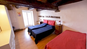 A room with two beds, wooden flooring, a window, and a door. - Casa la Finestra sul Lago - WelcHome (Cannobio)
