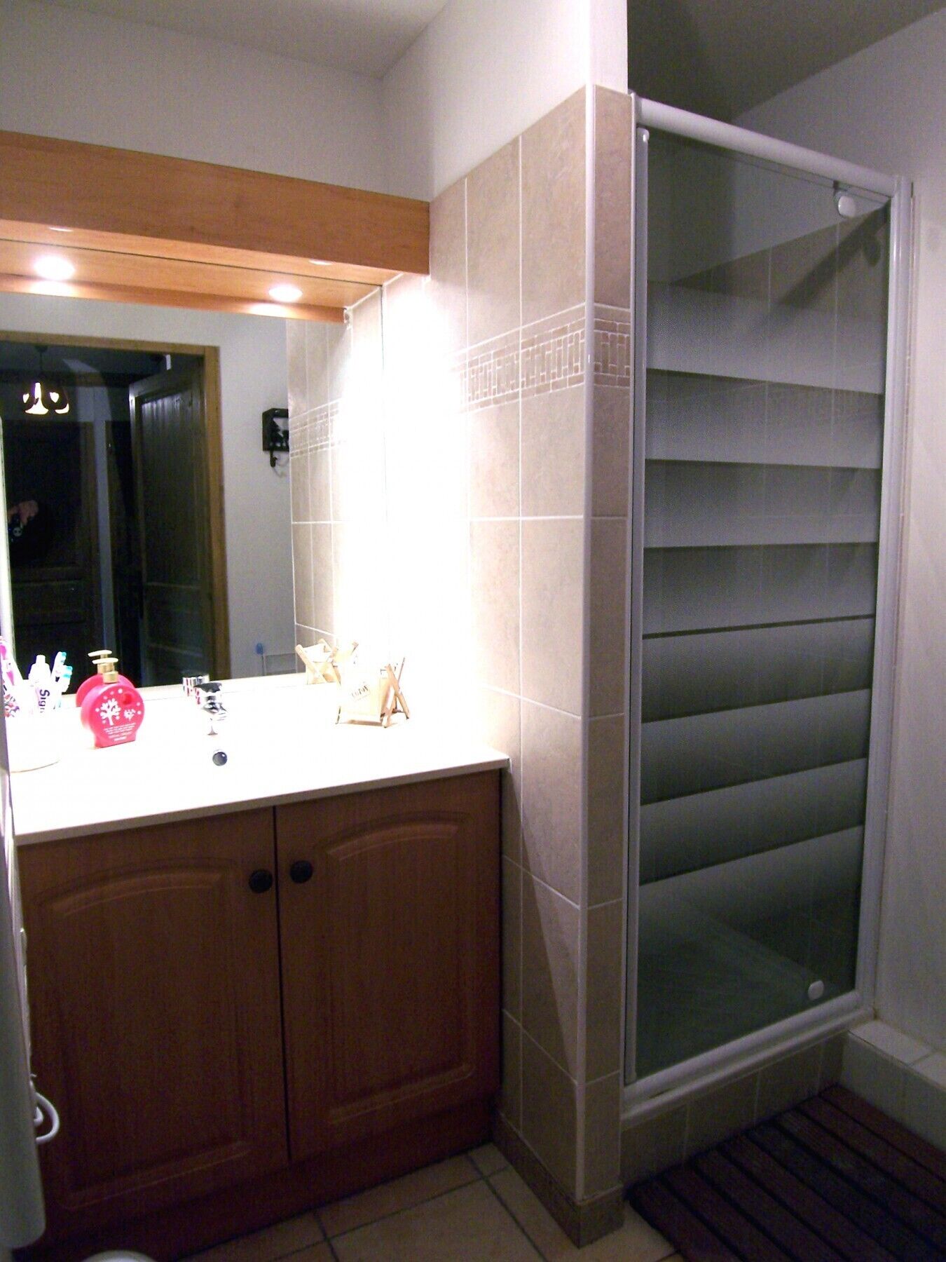 A bathroom with a wooden vanity, a glass shower enclosure, and a mirror above the vanity.
