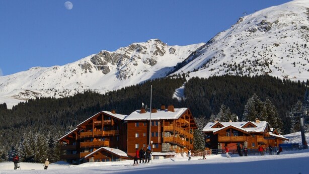 A wooden lodge with multiple balconies, surrounded by snow-covered mountains and a clear sky. - C202 - 42 m2 - 2P+Cab - 4/6 pers (Prapoutel)