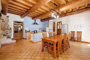 A spacious kitchen with a central island, wooden dining table, and chairs.