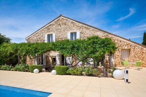 A stone building with a pool, surrounded by greenery and outdoor seating. - Homerez - Villa in Uchaux (Uchaux)