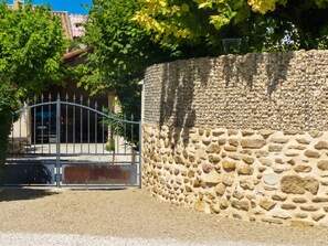 A stone wall with a metal gate leading to a building.