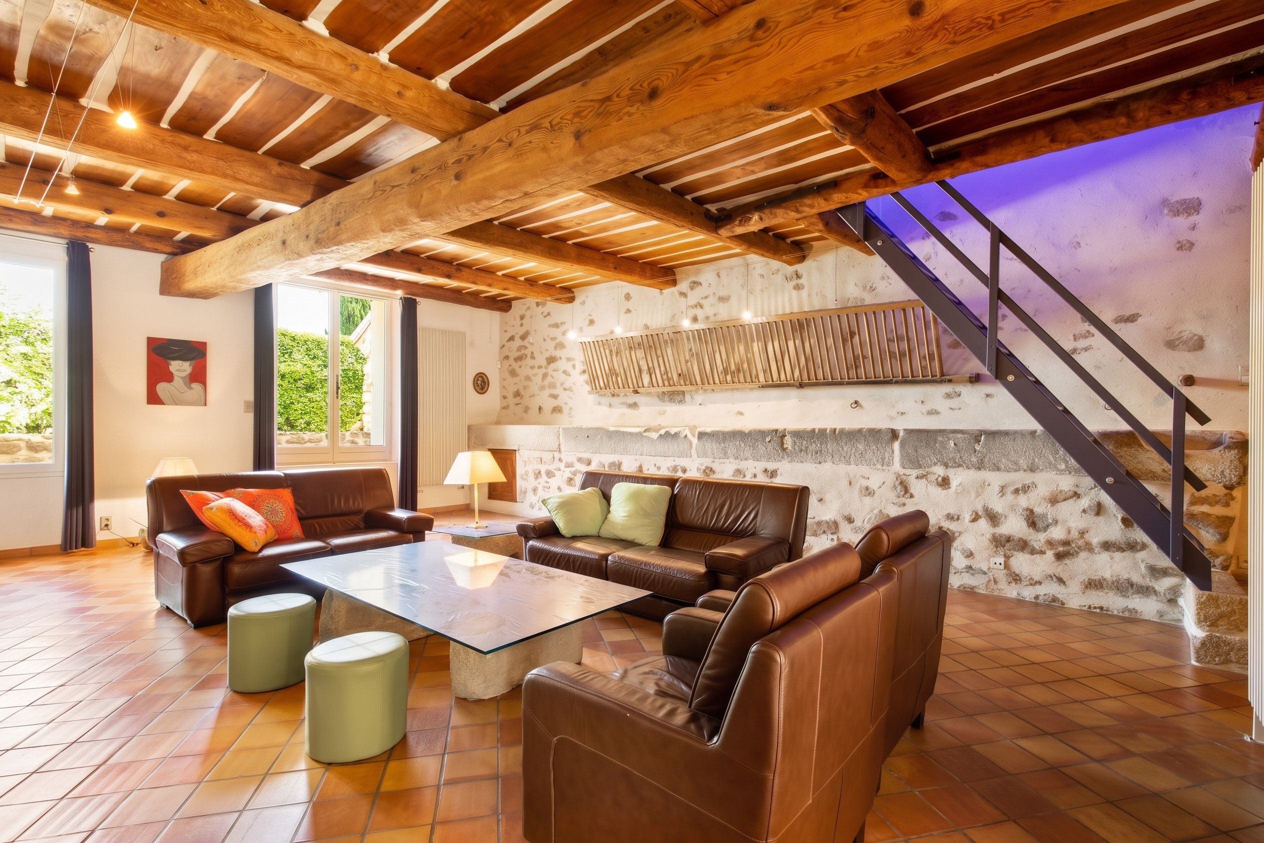 Ein geräumiges Wohnzimmer mit Ledersofas, einem Glastisch und einer Steinwand.