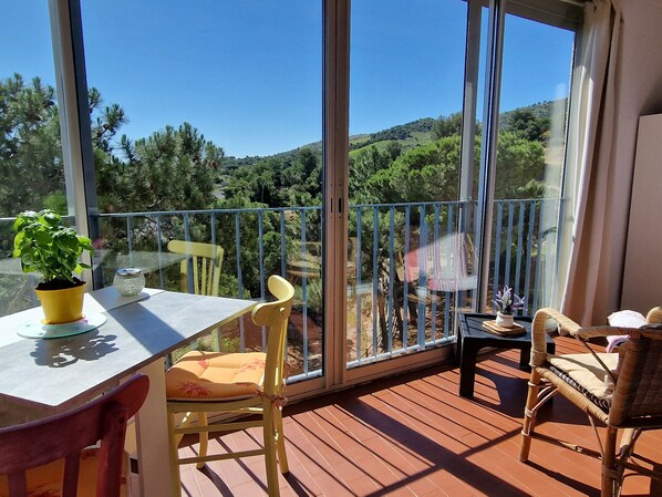 A balcony with a table, chairs, and a potted plant. - Apartment in Banyuls-sur-Mer with Sea View and Parking (Banyuls-sur-Mer)