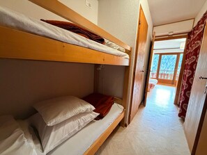 Una camera con un letto a castello, una testiera in legno, una coperta rossa e un cuscino bianco.
