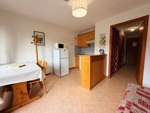 A compact kitchen with a refrigerator, microwave, and wooden cabinets. - Apartment for 4 with balcony and parking in Châtel (Châtel)