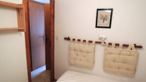 A bedroom with a wooden door, a bed with white bedding, and two beige headboards.
