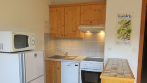 A compact kitchen with wooden cabinets, a microwave, a dishwasher, and an oven.