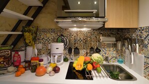 Uma cozinha com um fogão moderno, uma pia e diversos vegetais frescos na bancada.
