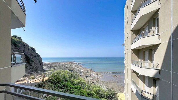 Un balcón con vista a una playa rocosa y el mar.