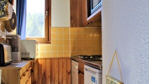 A compact kitchen with wooden cabinets, a microwave, a toaster, and a dishwasher. - Quiet studio cabin, ski-in/out, sleeps 4 - Risoul 1850 (Risoul)