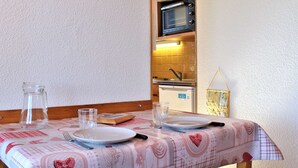 A dining table with a checkered tablecloth, a pitcher, and plates. A microwave is visible in the background. - Quiet studio cabin, ski-in/out, sleeps 4 - Risoul 1850 (Risoul)