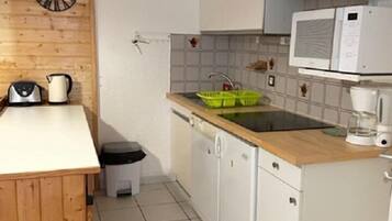 Een koelkast, een oven, een vaatwasser, kookgerei, borden en bestek