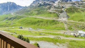 Un paisaje montañoso con cielo despejado, una carretera y un edificio de techo inclinado.