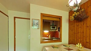 Un coin repas avec une table dressée pour quatre personnes, un four à micro-ondes placé au-dessus de l’évier et un mur en bois.