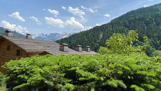 Un paysage de montagne avec un bâtiment en bois doté de plusieurs cheminées et un ciel dégagé.