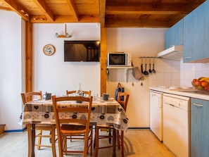 A kitchen with wooden cabinets, a microwave, a sink, and a dining table with chairs. - Cozy apartment 4 pers with parking, terrace, ski locker (Barèges)