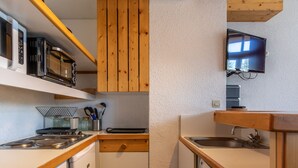 A compact kitchen with a microwave, stove, and sink. There is a wooden cabinet above the stove and a television mounted on the wall. - 3-room duplex for 6, valley view, near slopes, pets allowed in Arc 1800 (Les Arcs 1800)