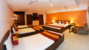 A hotel room with three beds, a sitting area, and a ceiling fan. - Hotel Palace (Amritsar)