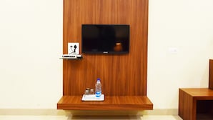 A wooden wall with a flat-screen TV mounted above a wooden shelf. - Hotel Palace (Amritsar)