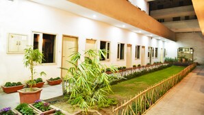 A building with multiple rooms, a garden area with potted plants, and a wooden fence. - Hotel Palace (Amritsar)