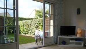 A living room with a TV, a table, and a chair. - Private Garden in Barfleur - Ground Floor Apartment (Barfleur)