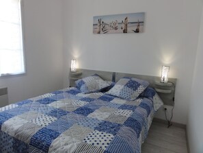 A bedroom with a bed, two bedside lamps, a painting on the wall, and a window.